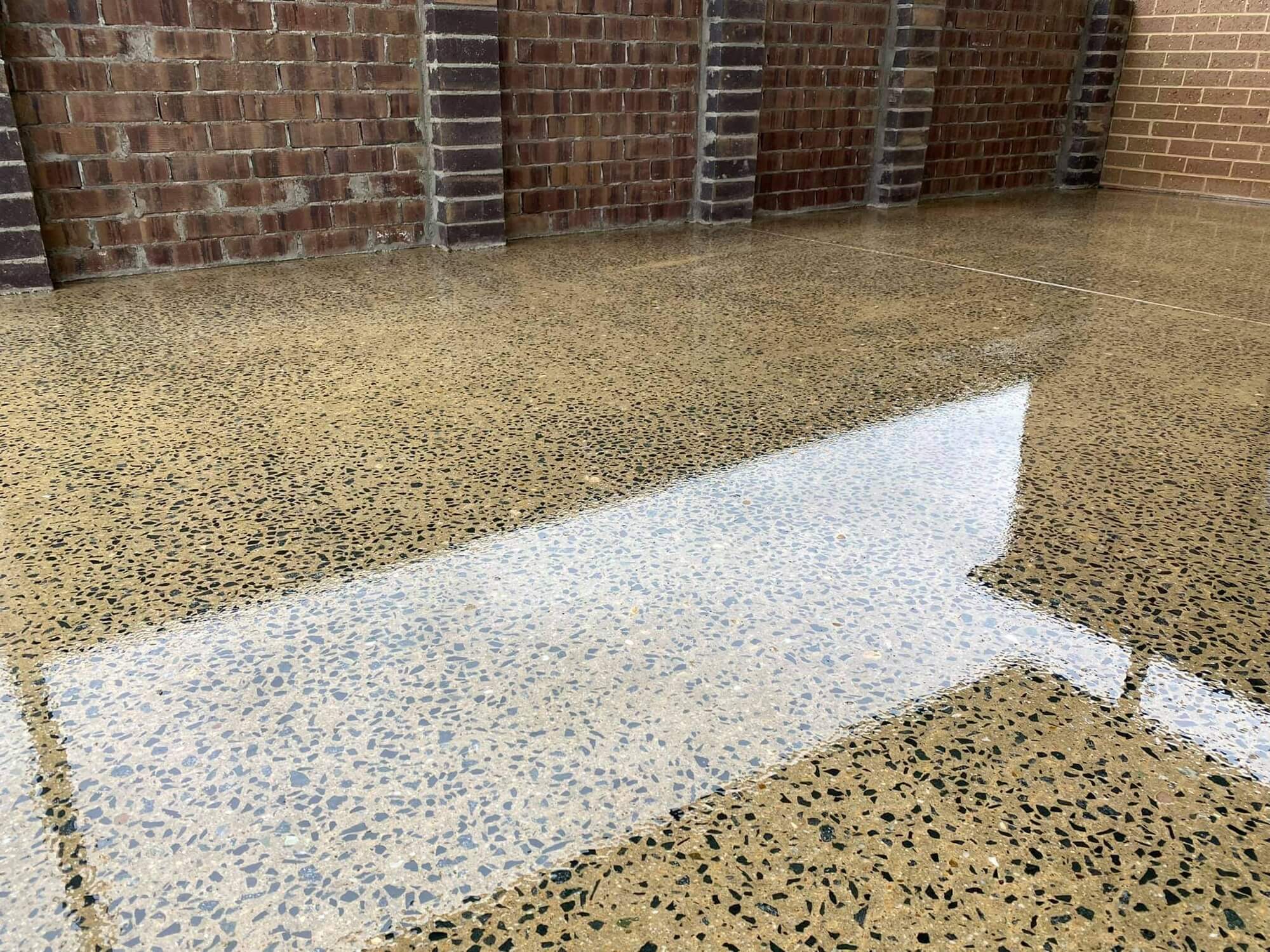 Polished concrete floor with full aggregate exposure reflecting the light across a large room