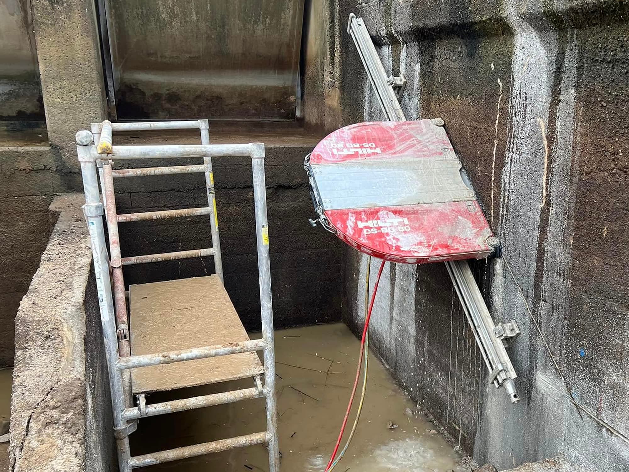 Hilti DS-BG 60 track mounted wall saw cutting down the wall of a flooded concrete pit