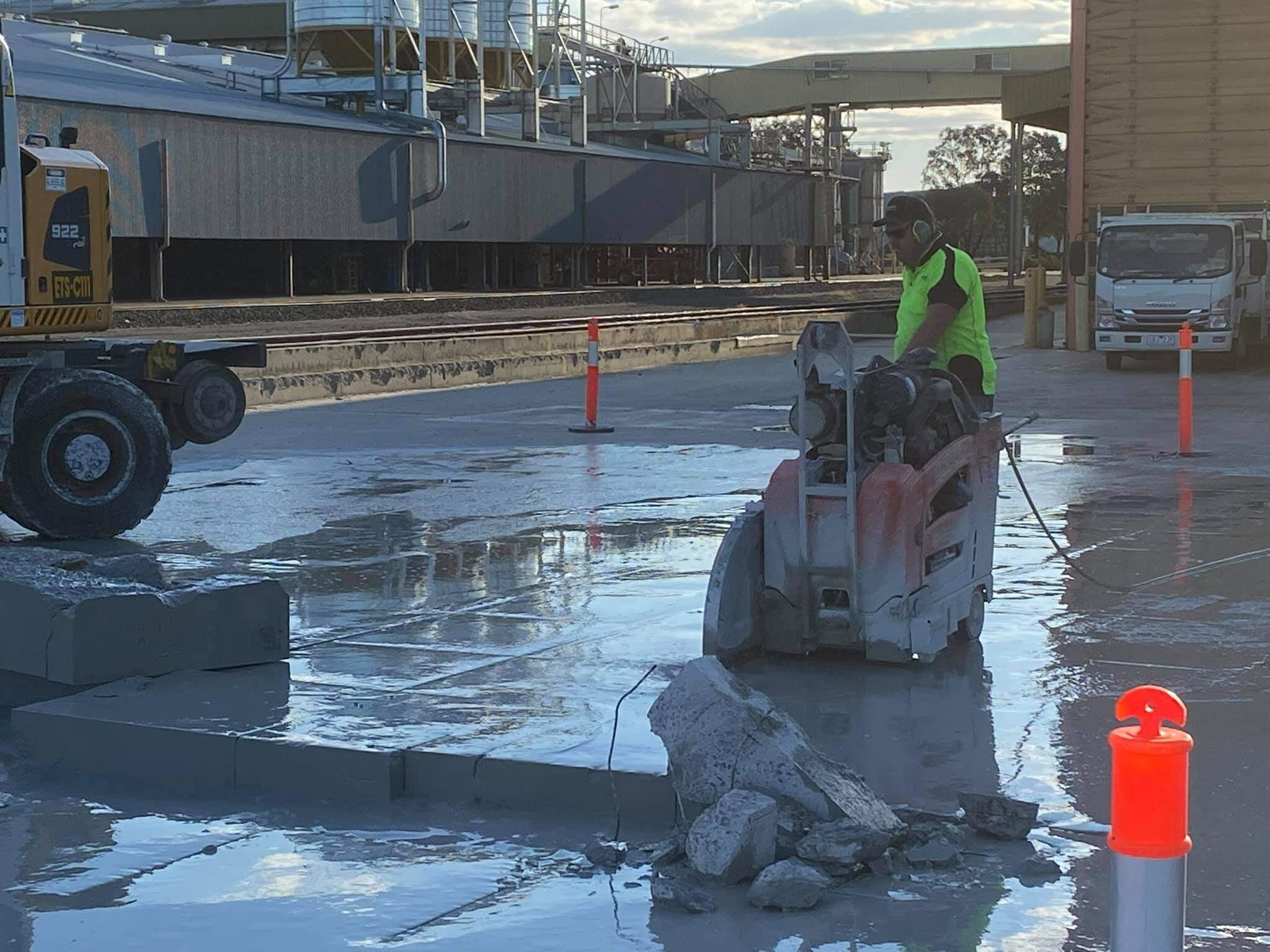Walk behind floor saw cutting a straight line across a wet industrial concrete slab