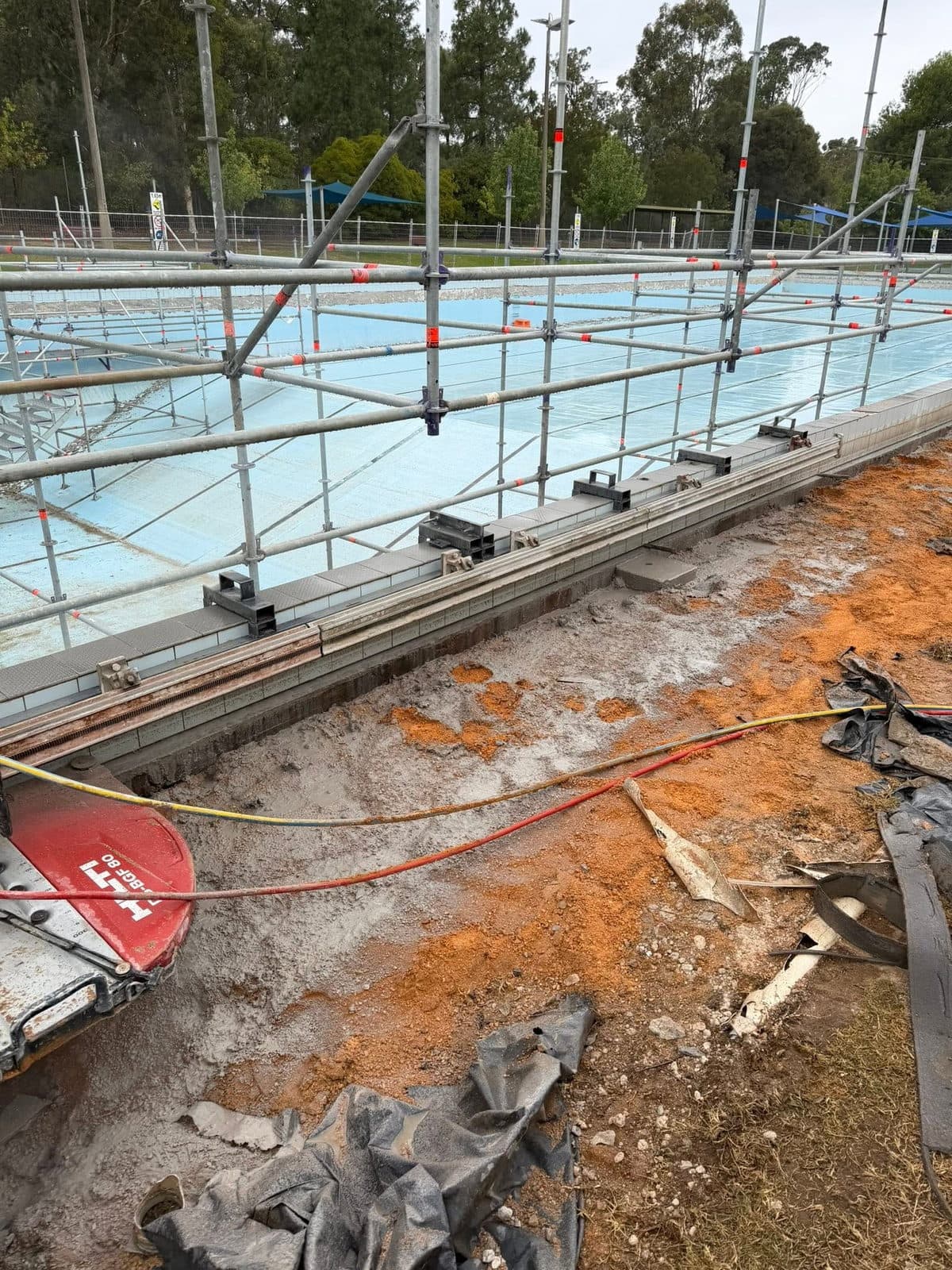 Wall saw running along a bolted track set up on pool coping