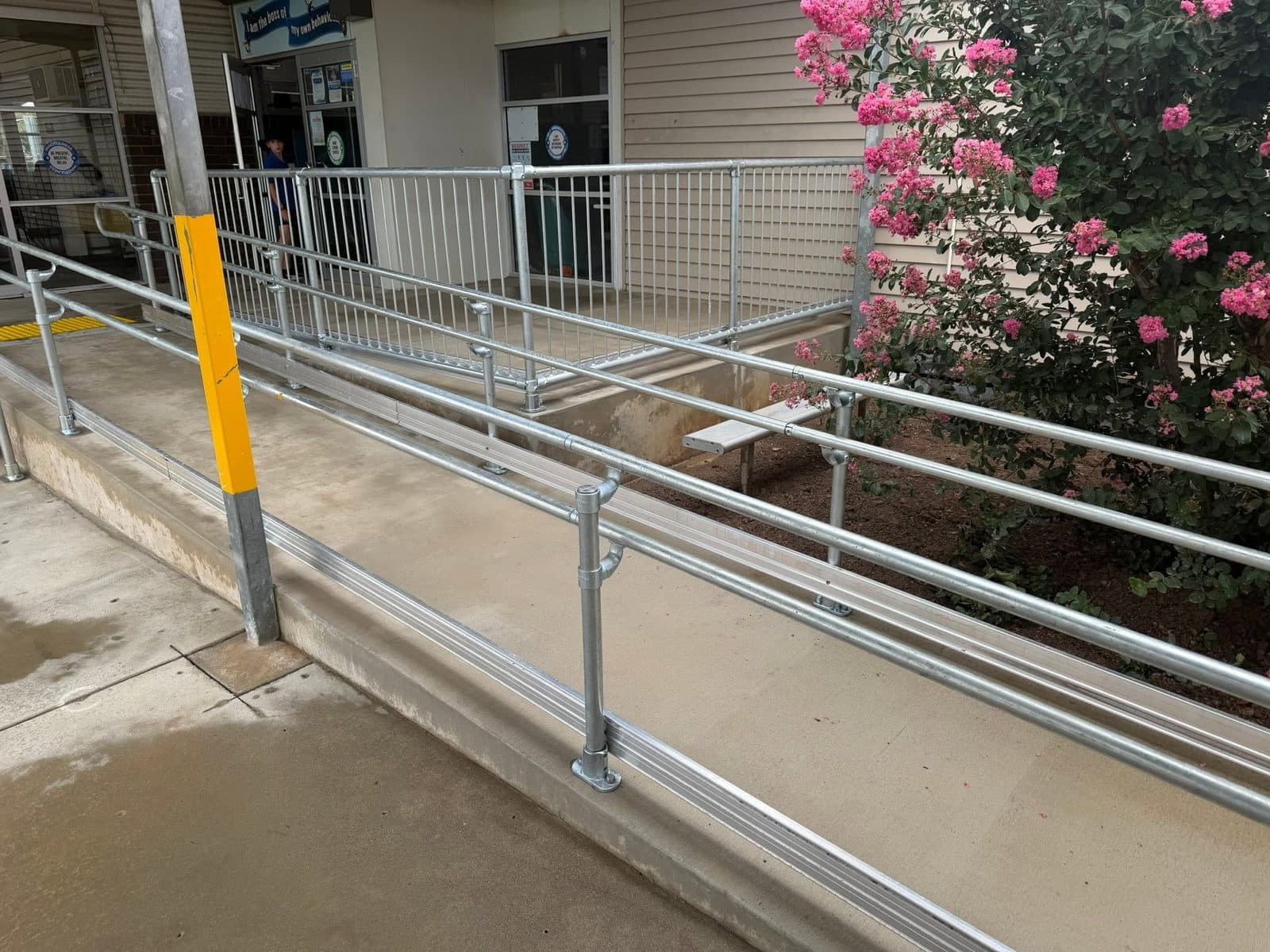 Completed access ramp with galvanised handrails at a Victorian school entrance